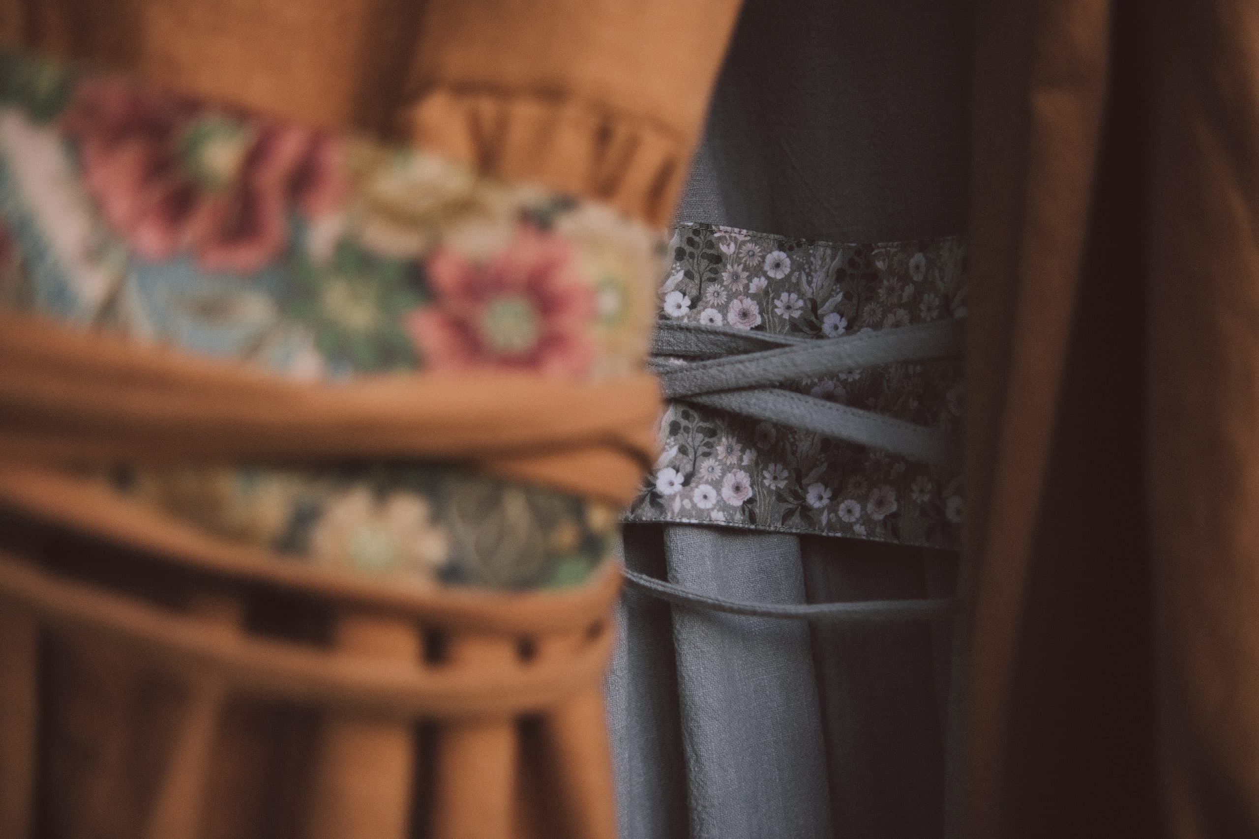 Two flowered sash bands — one on ochre cloth, one on grey-blue — up close